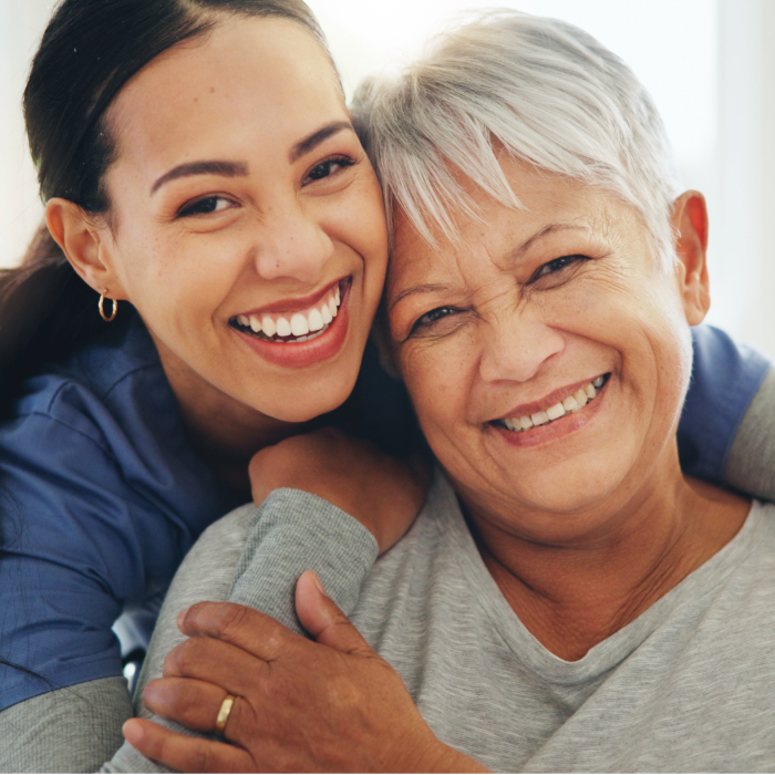 Caregiver and older adult smiling together during a supportive visit.