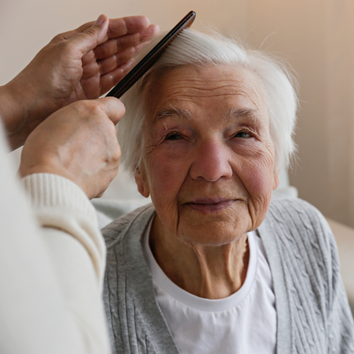 Older adult receiving gentle help with personal grooming at home.