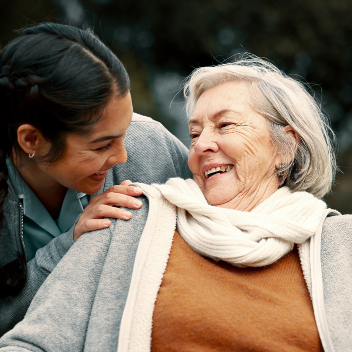 Caregiver smiling with an older adult during an in-home visit.