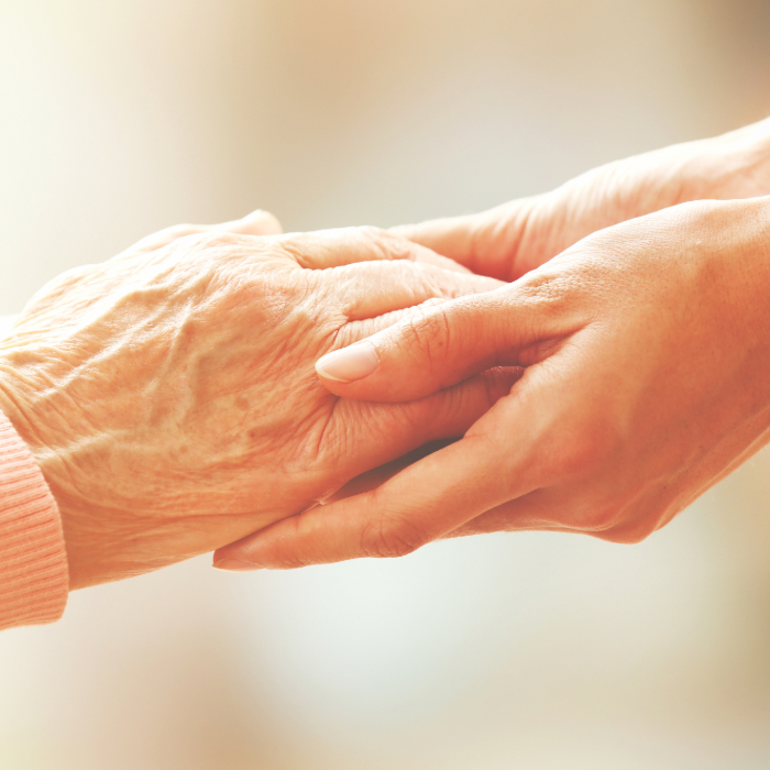 Caregiver holding an older adult’s hands in a comforting gesture.