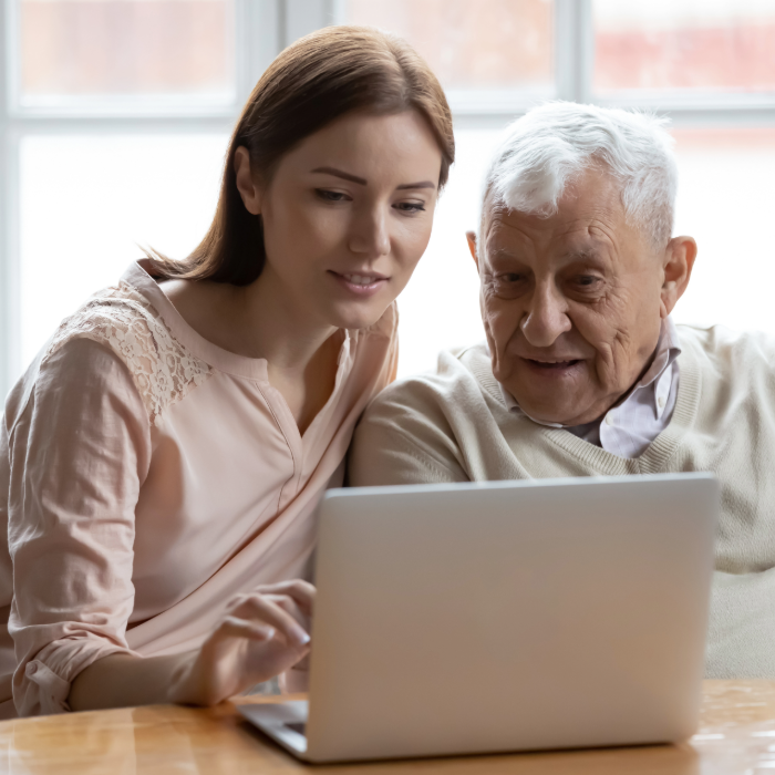 Staff member helping an older adult use a laptop to access information.