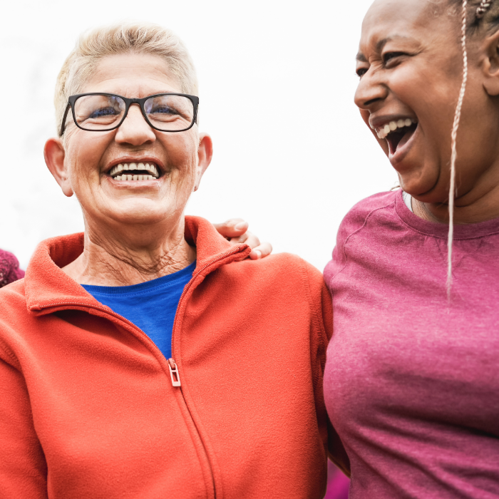 Two women smiling and laughing with an arm around each other.